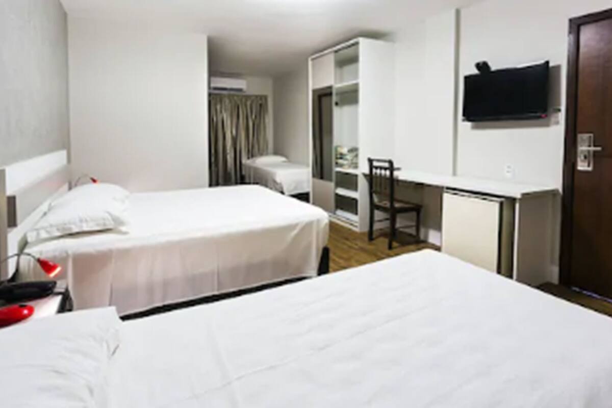 Habitación de hotel con dos camas, un escritorio, una silla, un televisor y un armario.