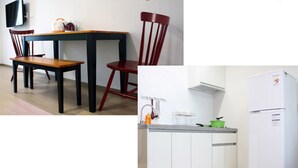 A dining area with a table and chairs, a kitchen with a sink and a refrigerator. - Gilgaon Pension (Jeju City)
