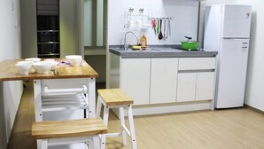 A compact kitchen with a wooden countertop, white cabinets, and a white refrigerator. - Gilgaon Pension (Jeju City)