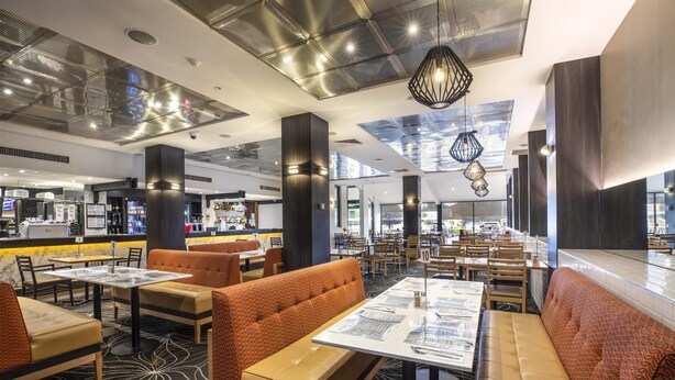 A modern restaurant with high ceilings, large windows, and a variety of seating options including booths and tables. - Nightcap at Millers Inn (Altona North)