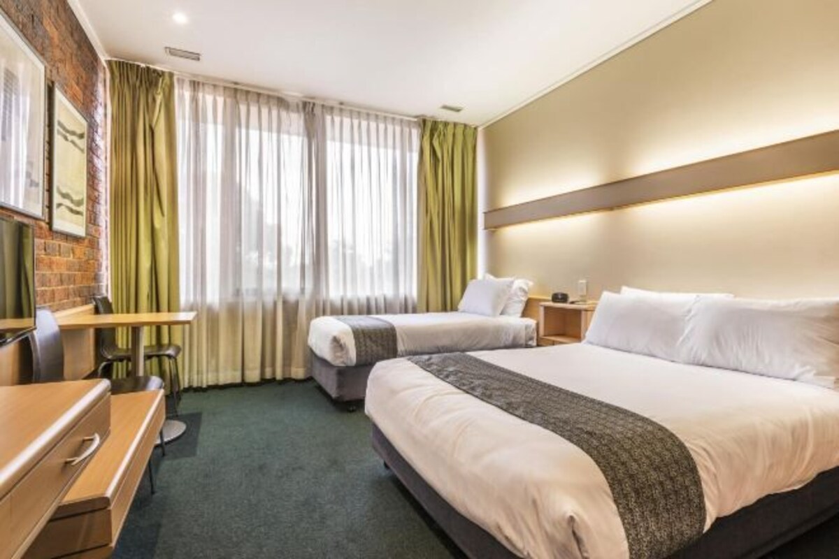 Habitación de hotel con dos camas, un escritorio y una silla.