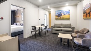 A hotel room with a bed, a dining area with a table and chairs, a sofa, and two paintings on the wall. - Nightcap at Millers Inn (Altona North)