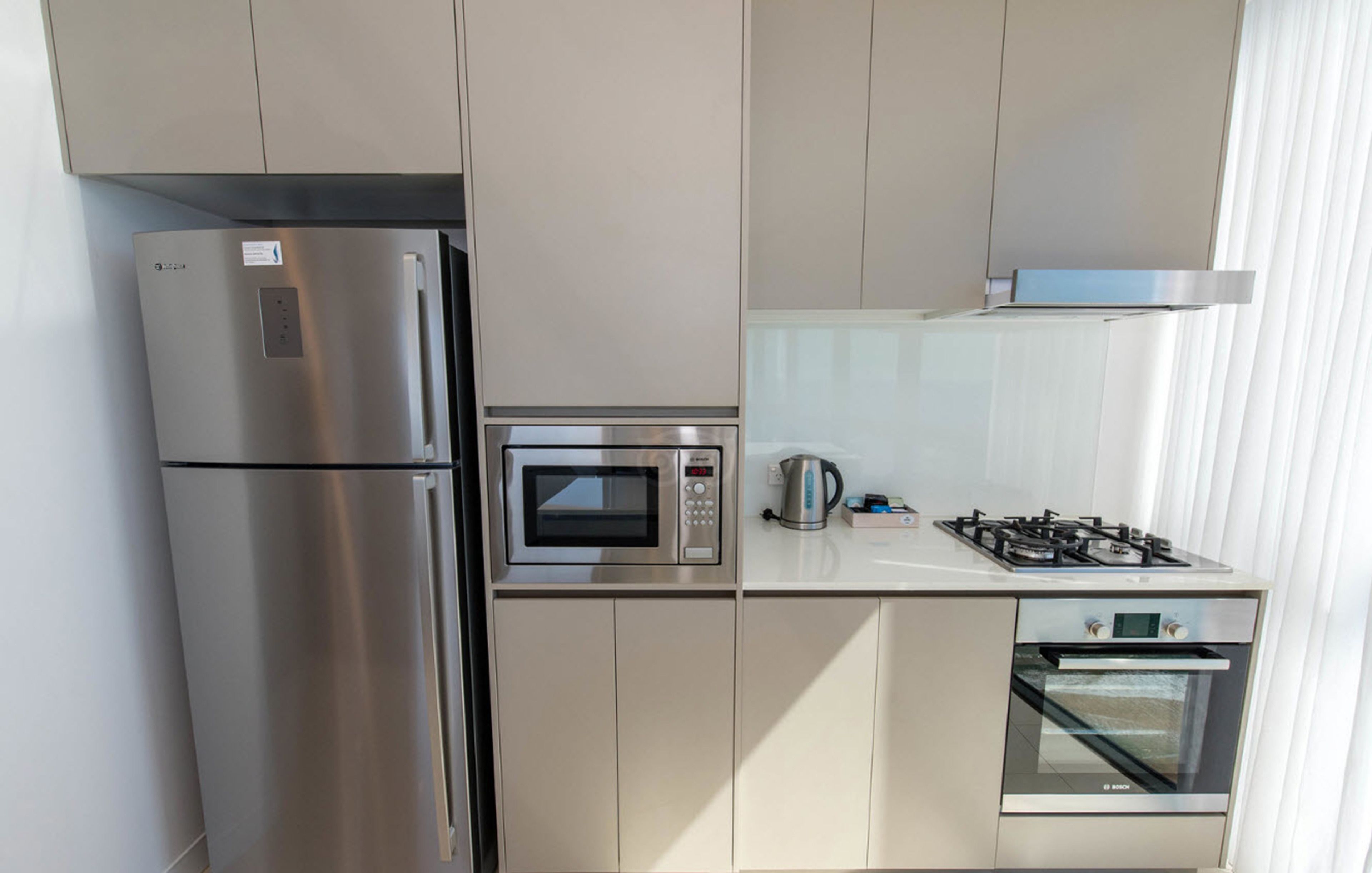 Eine moderne Küche mit Edelstahlgeräten, darunter ein Kühlschrank, eine Mikrowelle, ein Wasserkocher und ein Backofen.