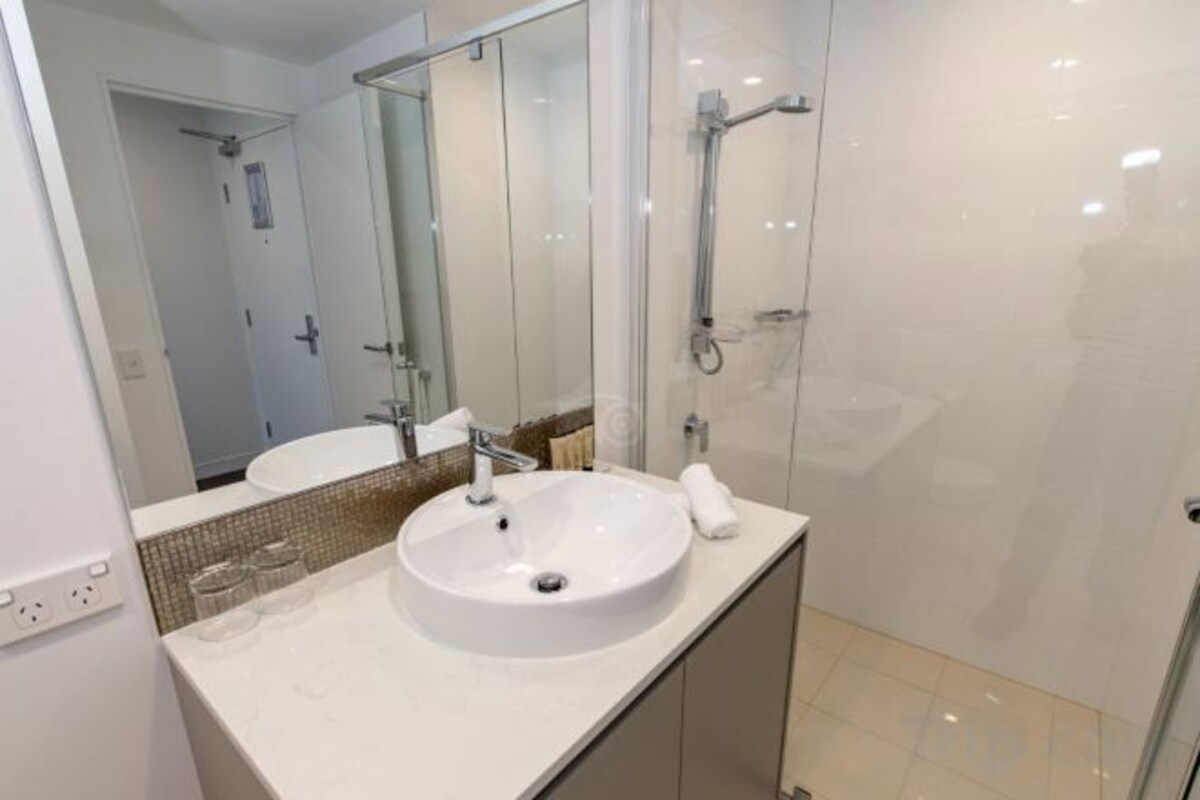A bathroom with a white sink, a mirror, and a shower.