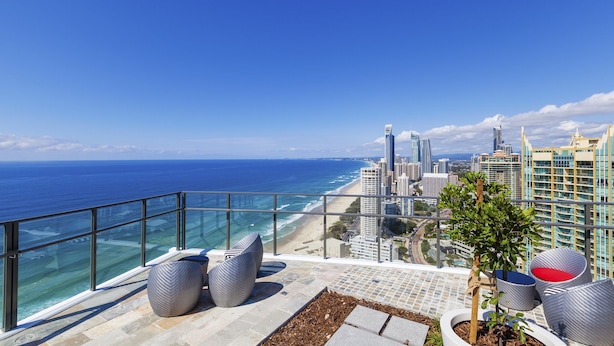 Un balcon offrant une vue sur l’océan et le paysage urbain.