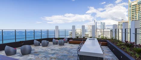 Eine Dachterrasse mit Sitzgelegenheiten, einer Bar und Blick auf die Stadtlandschaft und das Wasser.