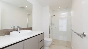 A modern bathroom with a white sink, a toilet, and a glass-enclosed shower.