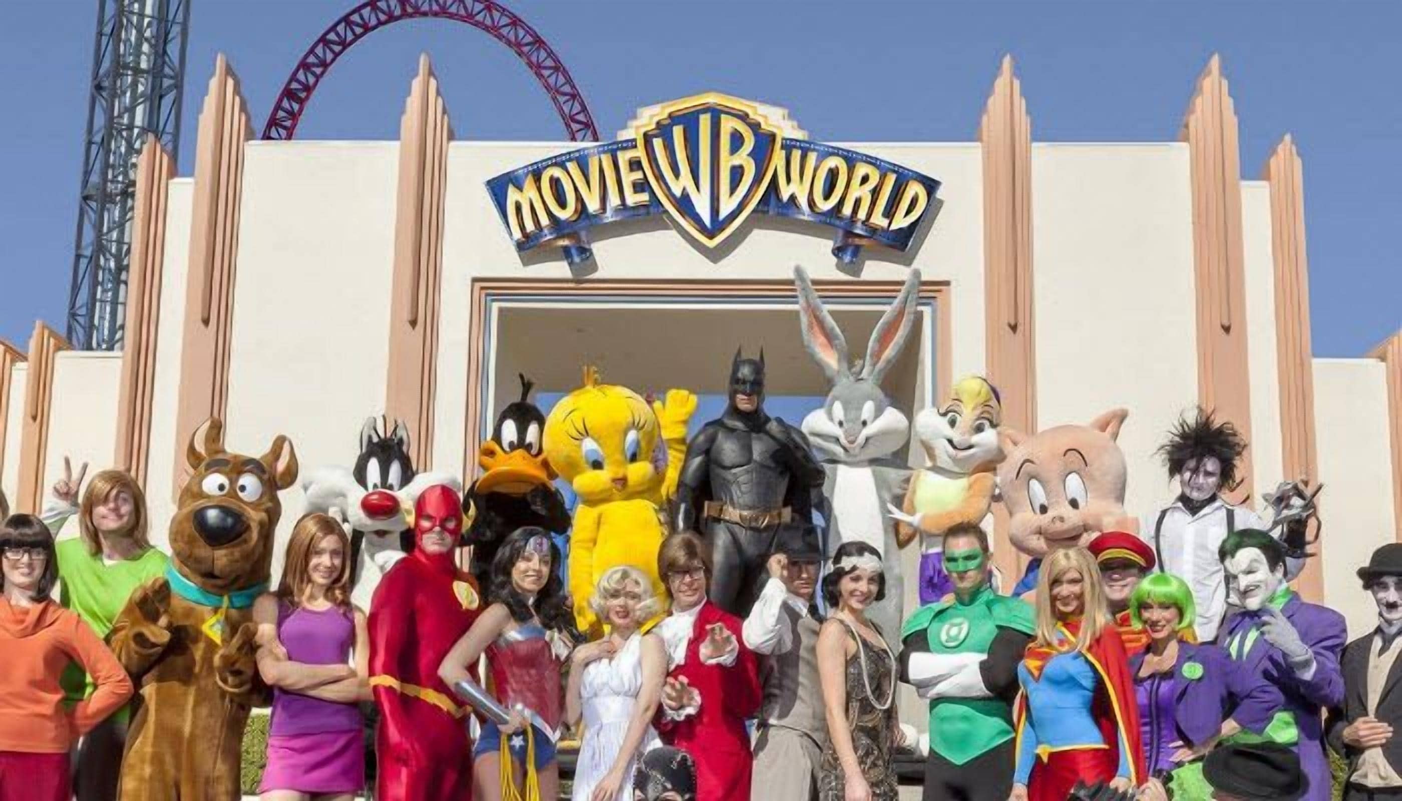 A group of people in various costumes in front of a building with a sign that reads "MOVIE WORLD".