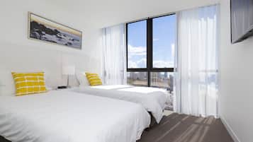 A hotel room with two beds, a large window with curtains, a painting on the wall, and a flat-screen TV.