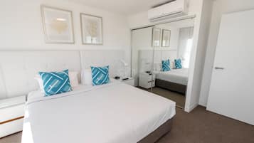 Een moderne hotelkamer met een groot bed, nachtkastjes, een spiegel en een airconditioning.