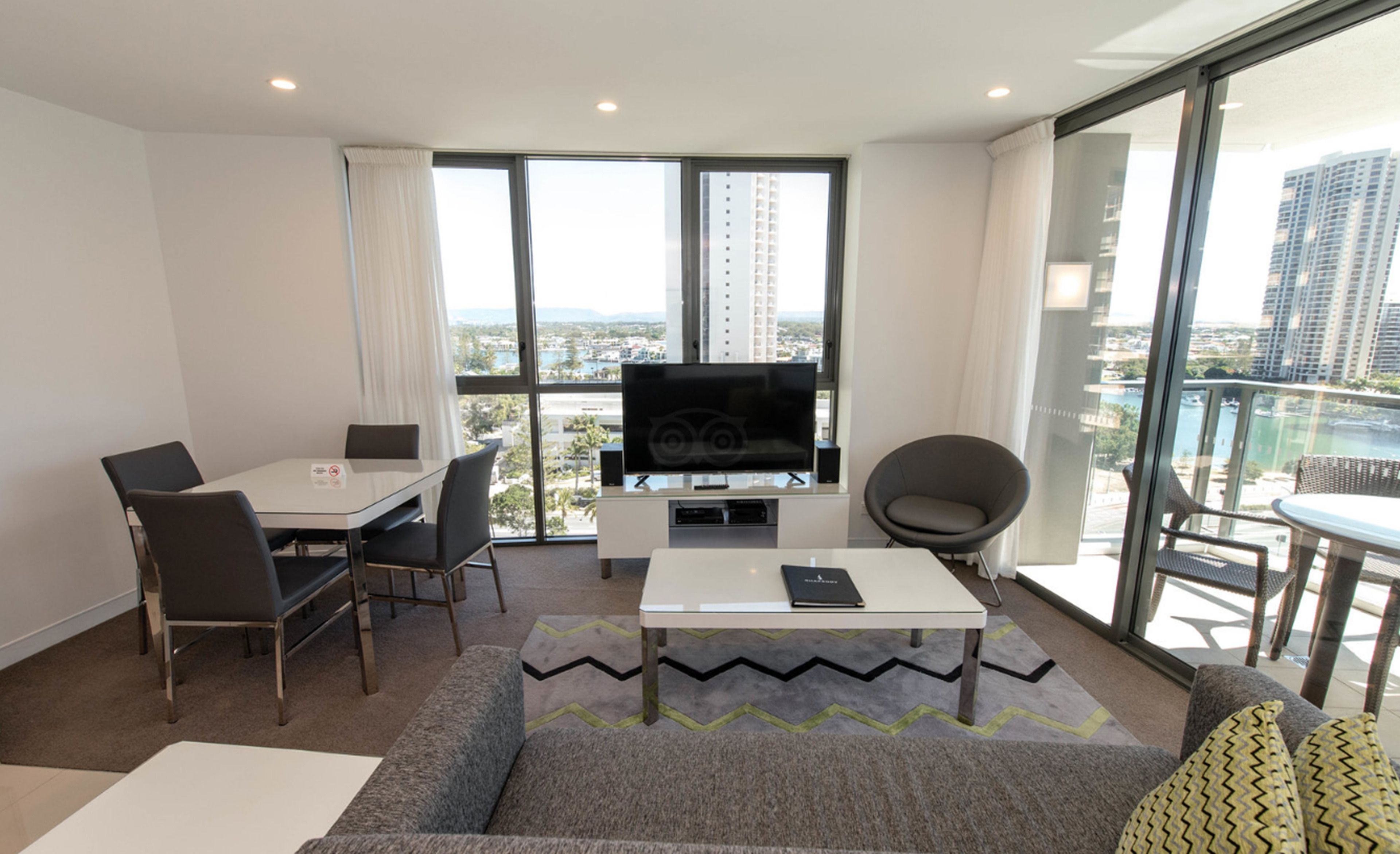 A modern living room with a flat-screen TV, a dining table, and a sofa.