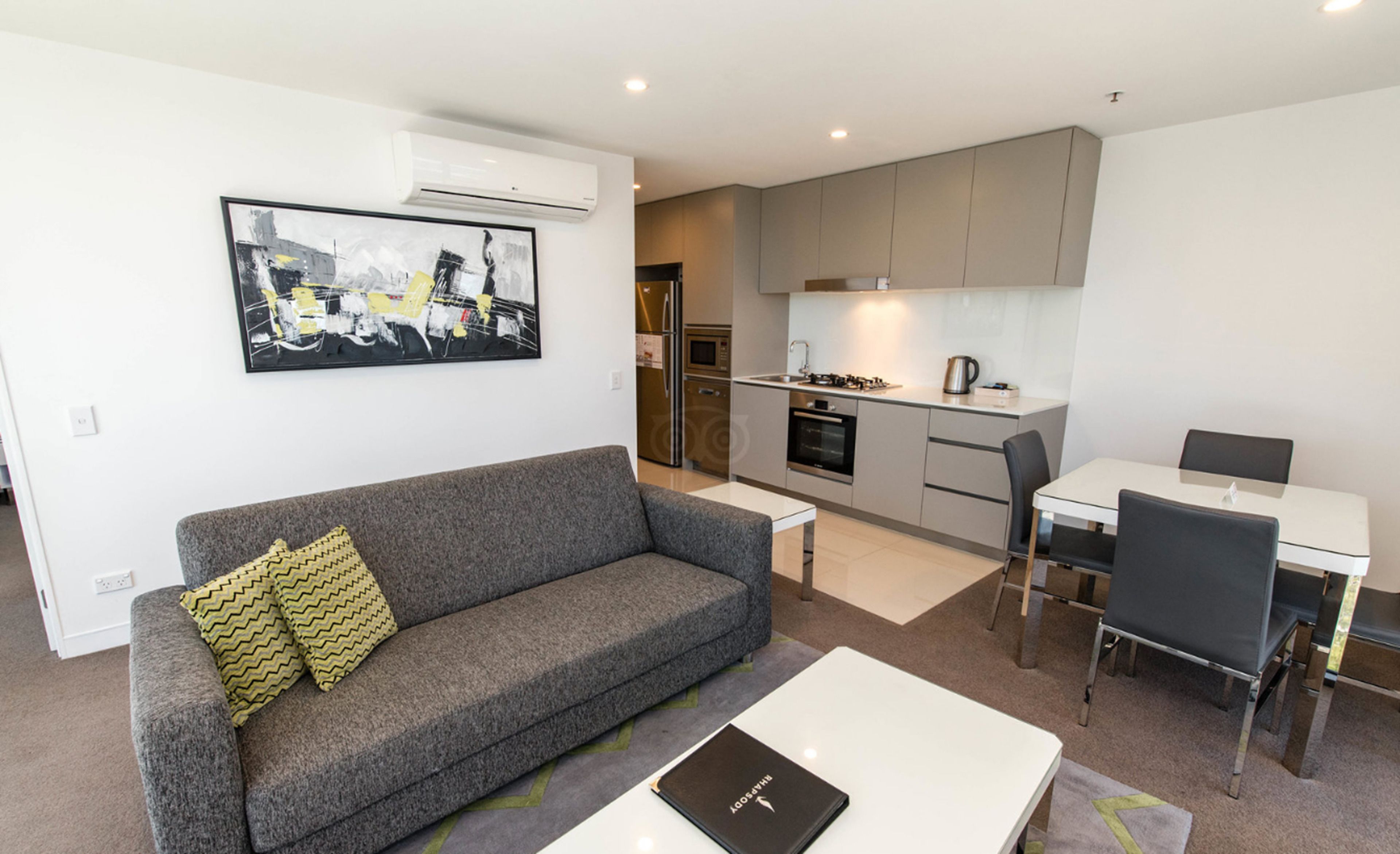 Un appartement moderne avec un canapé gris, une table à manger et un coin cuisine.
