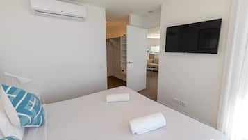 Ein Hotelzimmer mit einem Bett, einem an der Wand befestigten Fernseher und einer Klimaanlage über dem Bett.