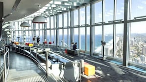 Un vaste atrium doté de hauts plafonds et de grandes fenêtres offrant une vue sur la ville et l’océan.