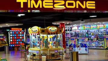 Een helder verlichte indoor speelhal met diverse spelautomaten en een winkel die speelgoed en games verkoopt.