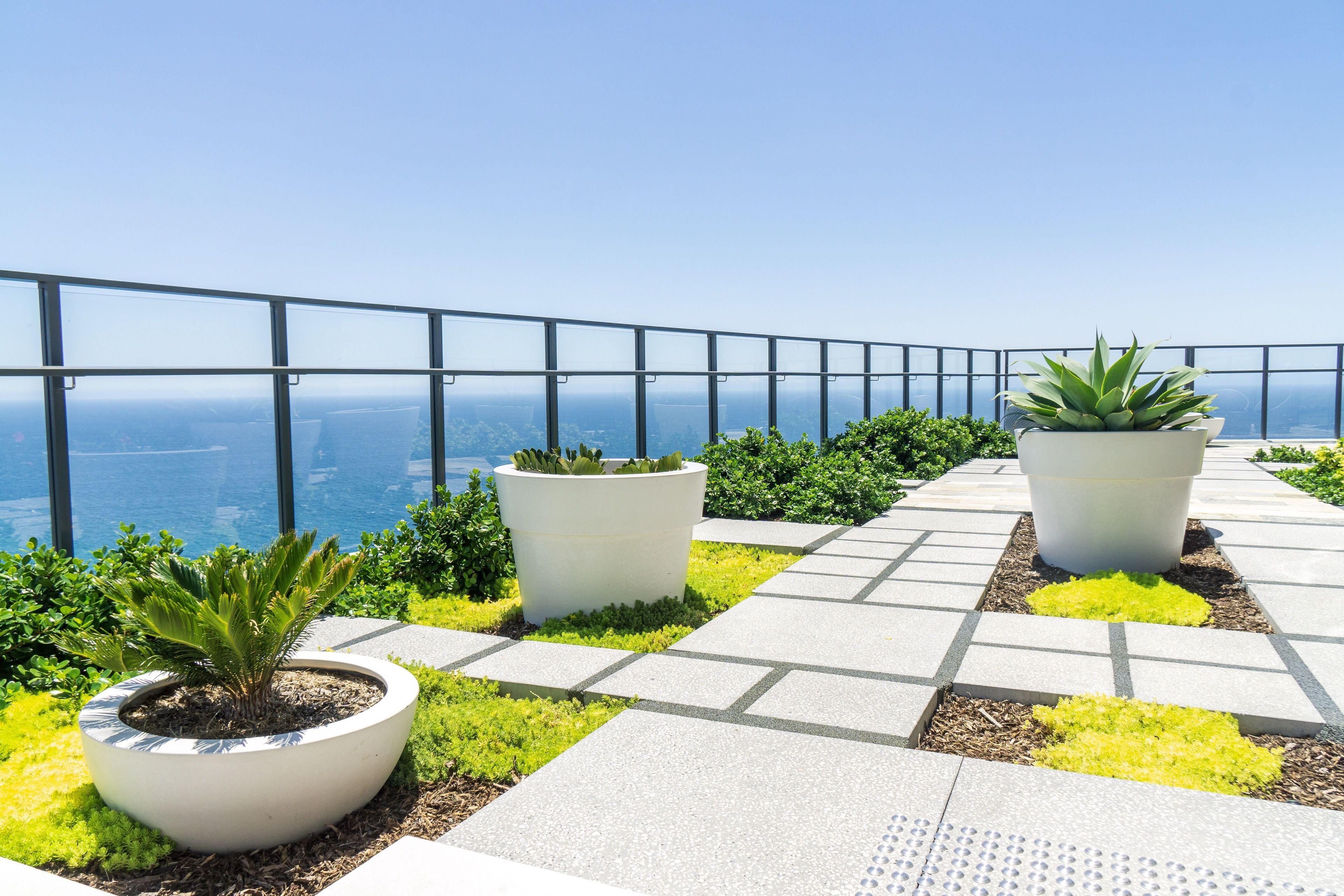 Un jardin sur le toit, agrémenté de plantes en pot, offrant une vue dégagée sur l’océan.
