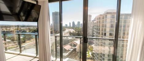 Una habitación de hotel moderna con ventanas de gran altura y vistas panorámicas de la ciudad, además de un televisor de pantalla plana.