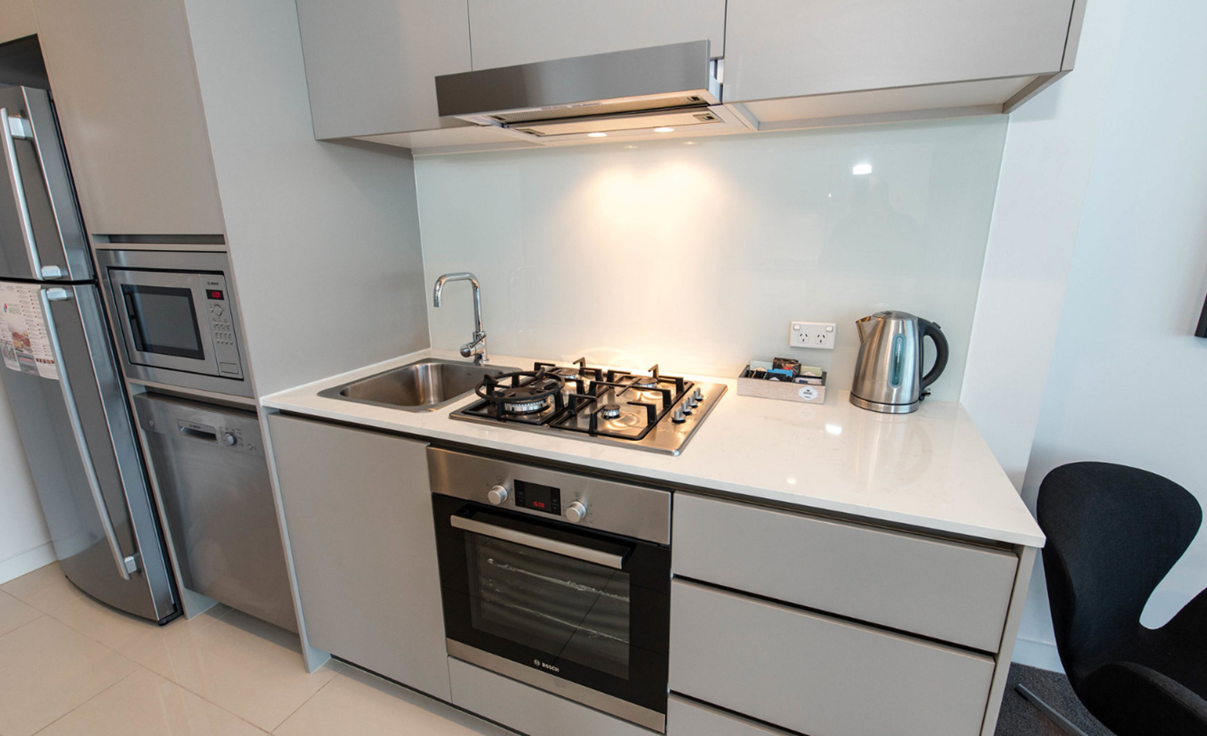 A modern kitchen with stainless steel appliances, a gas stove, oven, and a kettle.