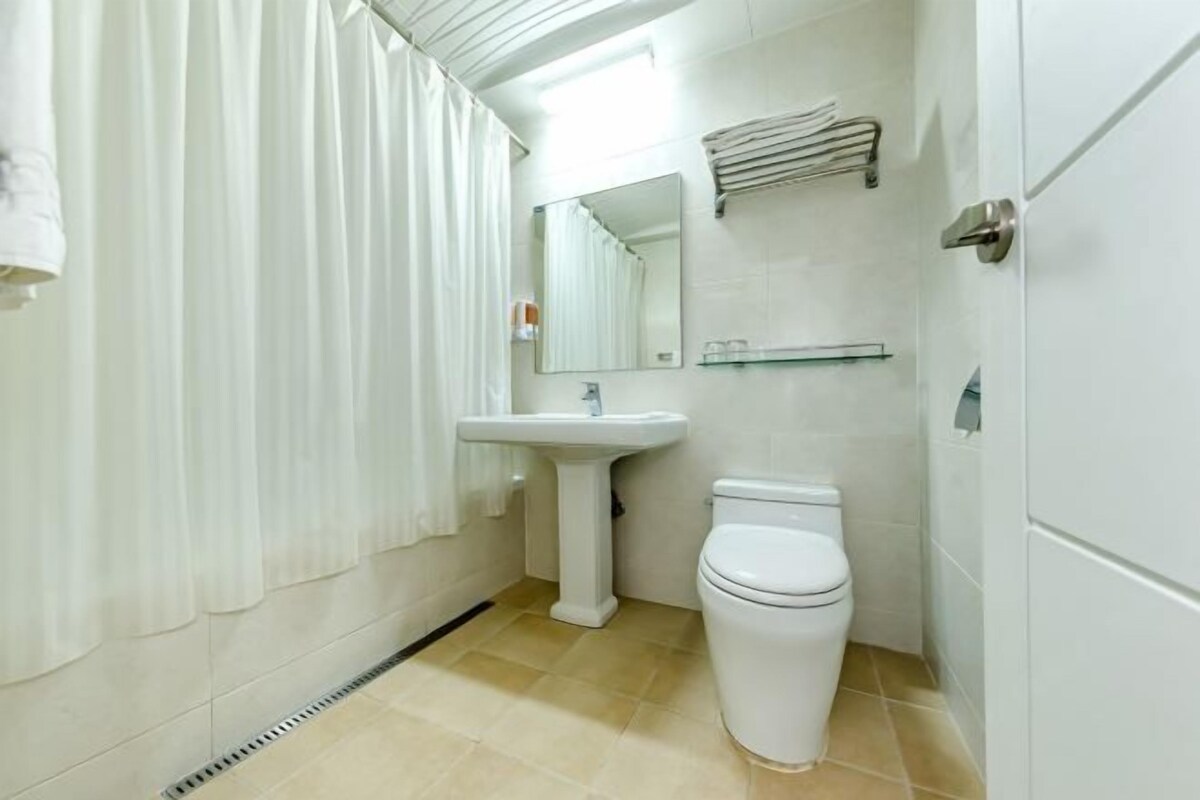 Une salle de bain comprenant un lavabo sur colonne, des toilettes, un miroir et un porte-serviettes.