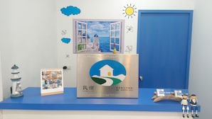 A hotel reception desk with a view of a seaside scene through a window, a decorative lamp, a framed photo, and a sign with a QR code. - Simple Travel - Hostel (Donggang)