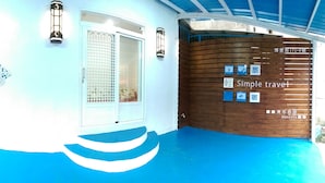 A hotel interior with a blue floor, a white door, and a wooden wall with travel-related signage. - Simple Travel - Hostel (Donggang)