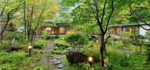 Un jardin japonais traditionnel, avec un sentier, des rochers et un bâtiment à l’extérieur en bois.