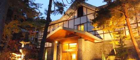 Un edificio moderno con fachada de piedra, un alero de madera y una entrada de piedra.