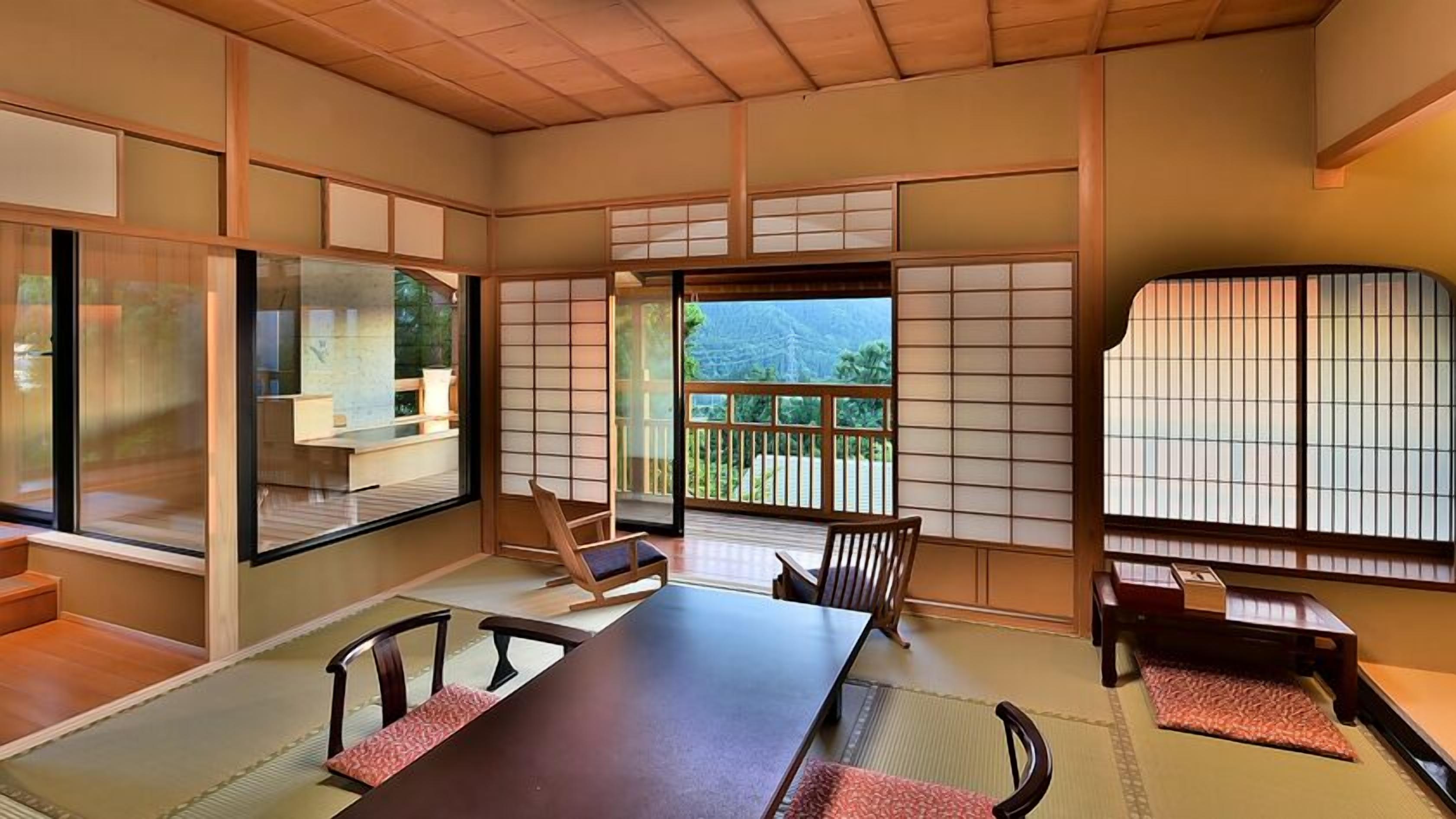 A traditional Japanese room with tatami flooring, sliding doors, and a view of a mountainous landscape.