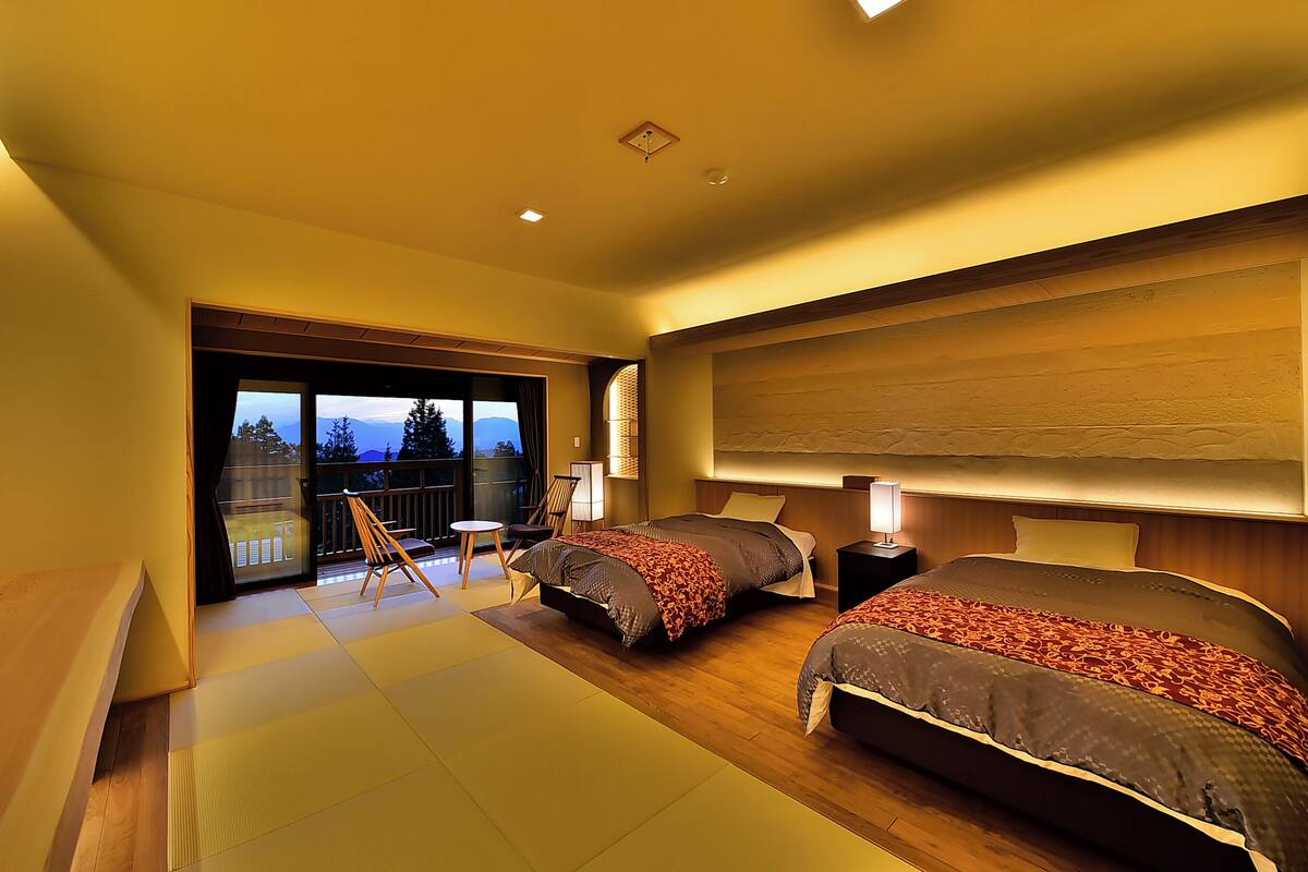 Een moderne hotelkamer met twee bedden, een balkon en uitzicht, en een houten vloer.