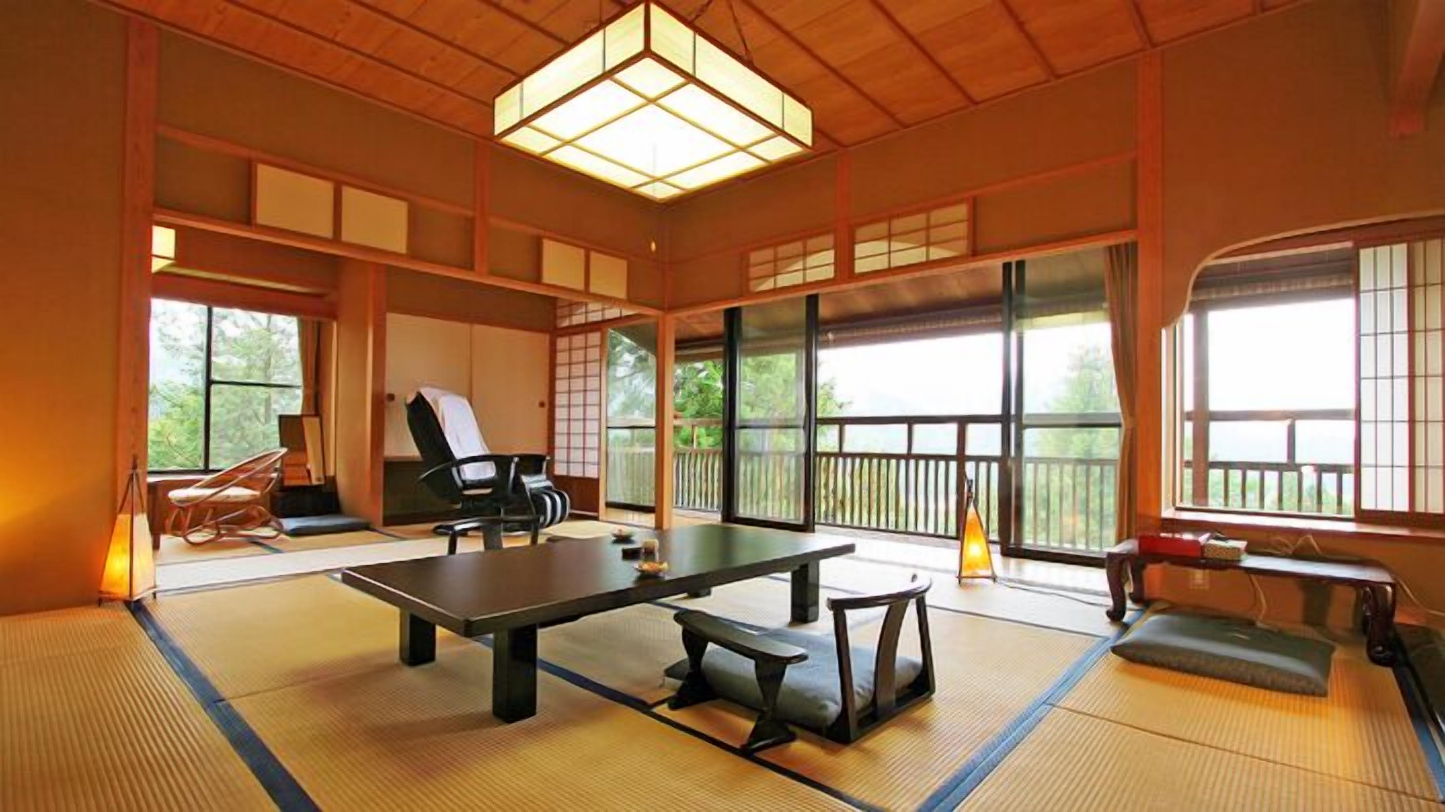 A traditional tatami mat room with a tatami mat table, a black chair, and a view of the outdoors through large windows.