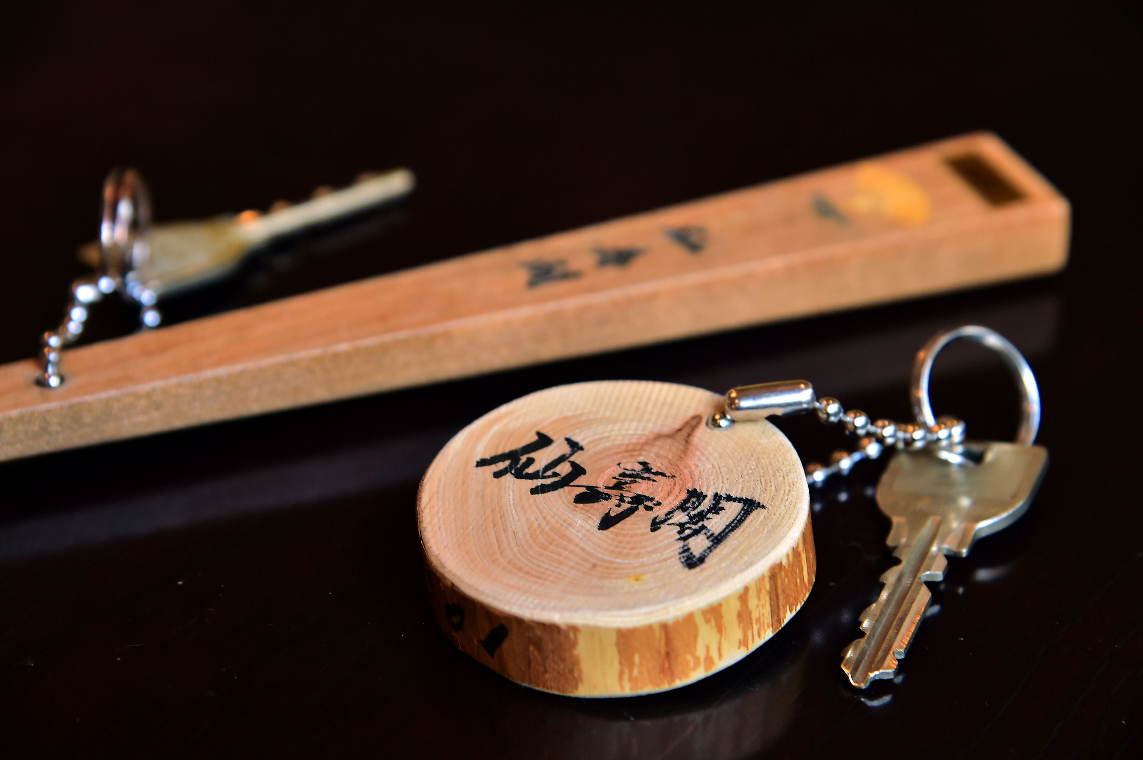 A wooden keychain with a circular wooden piece and a rectangular wooden key holder with Chinese characters.