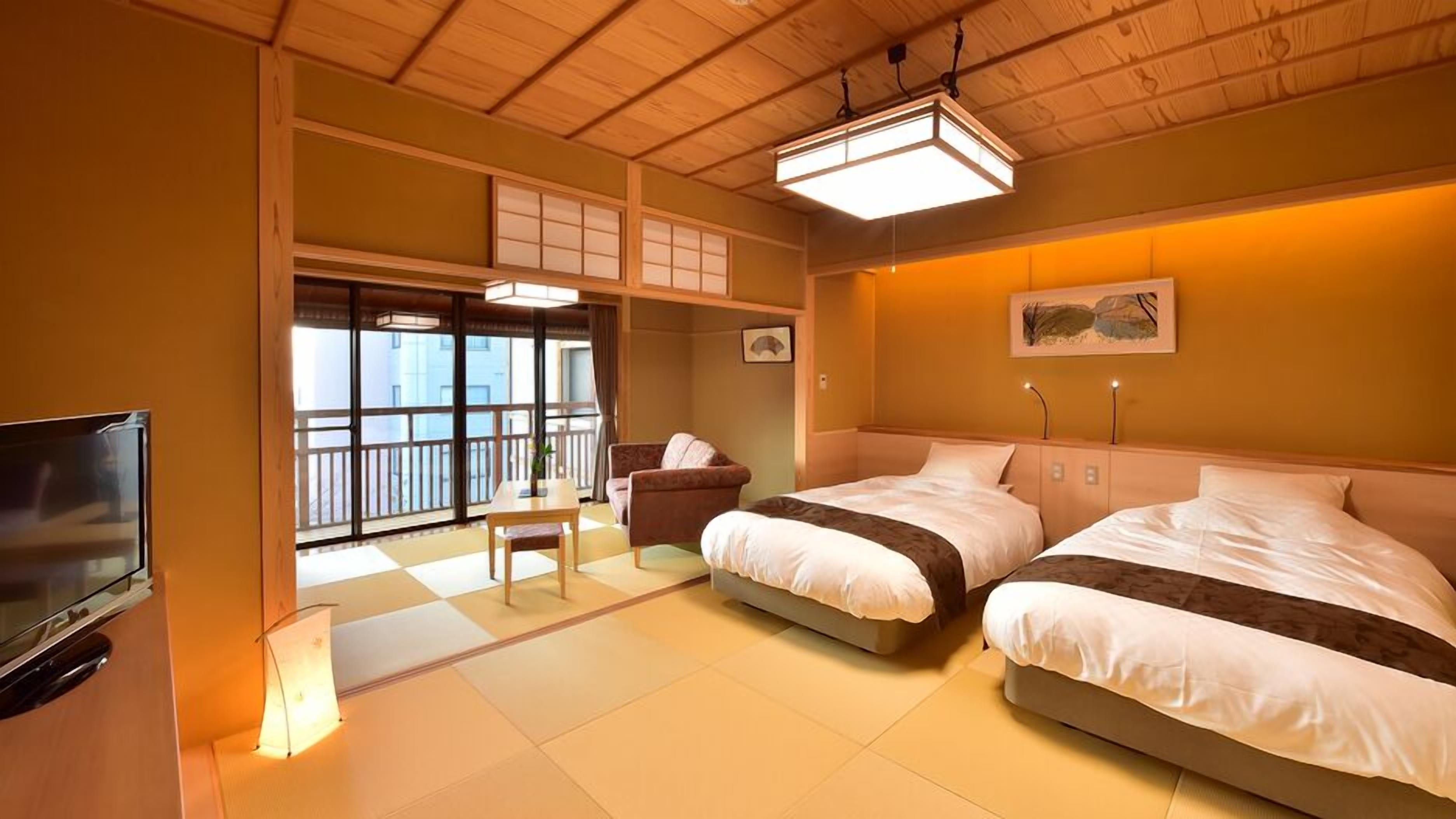 A hotel room with two beds, a television, a desk, and a view through large windows.