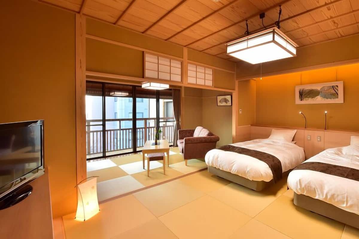 Een hotelkamer met twee bedden, een televisie, een bureau en uitzicht door grote ramen.