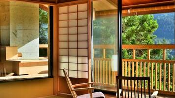 A traditional Japanese-style room with tatami flooring, sliding shoji doors, and a view of lush greenery outside.