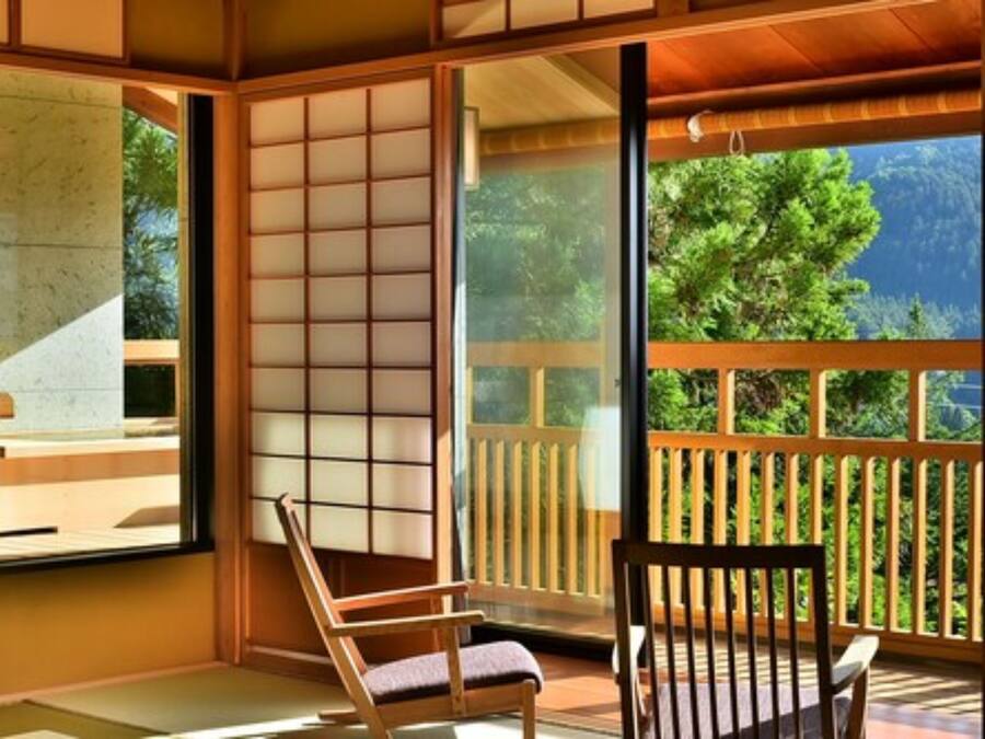 A traditional Japanese-style room with tatami flooring, sliding shoji doors, and a view of lush greenery outside.