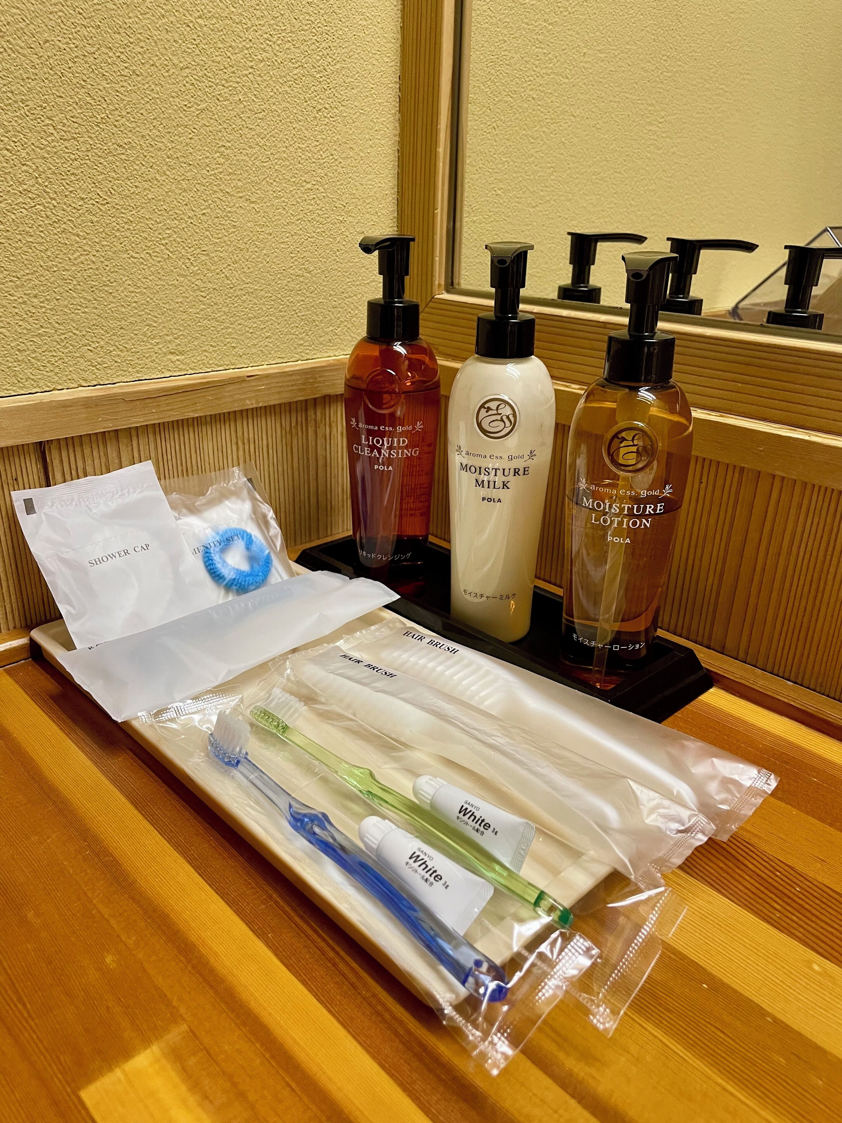 Artículos de tocador como gorro de ducha, cepillo para el cabello y diversos productos de cuidado personal sobre una mesa de madera.