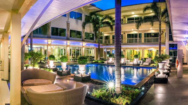 Um hotel moderno com área de piscina, espaço para sentar ao ar livre e vários andares.