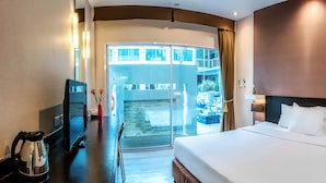 Quarto de hotel com cama, televisão, cafeteira e vista para a varanda.