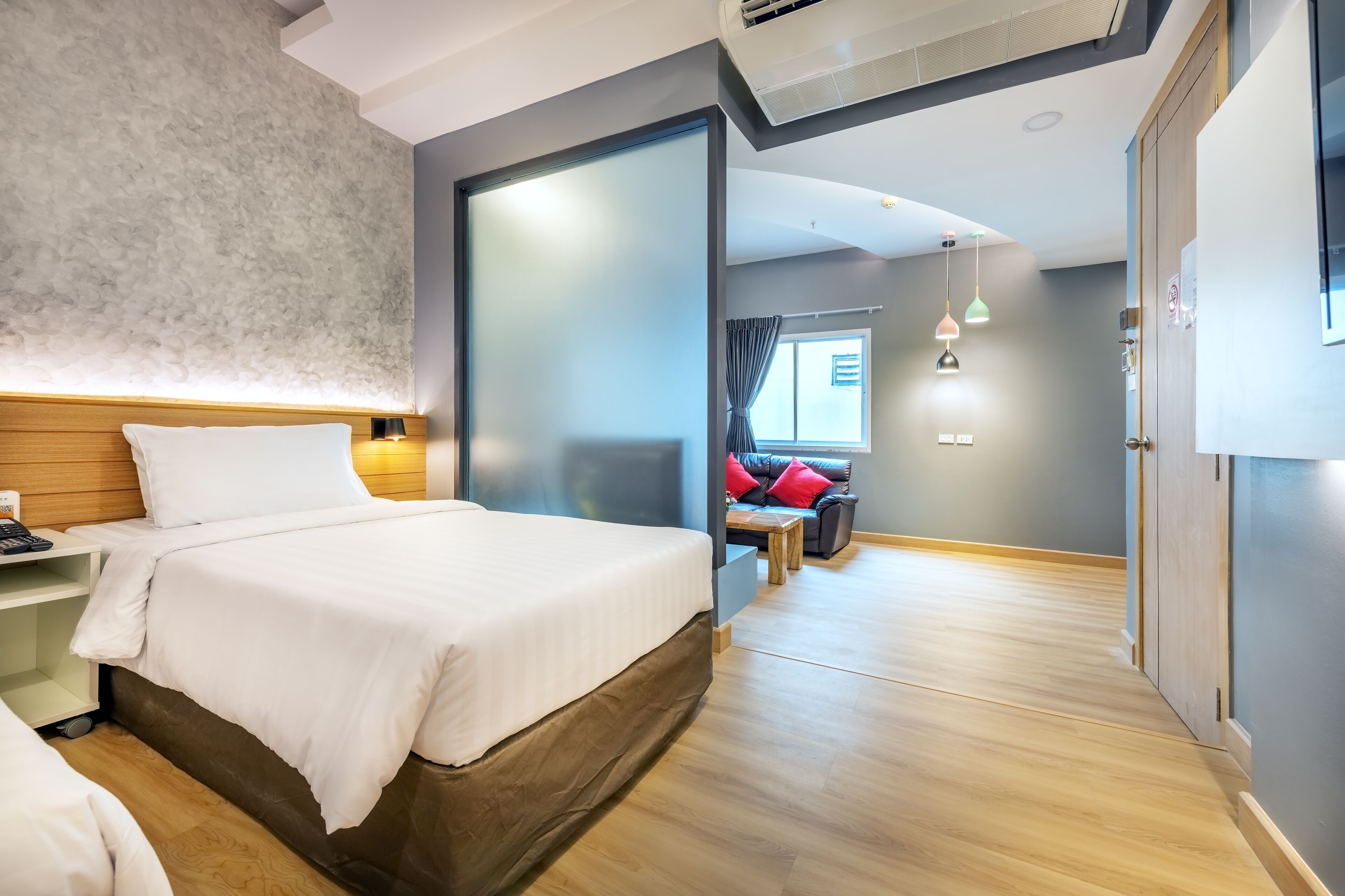 A modern hotel room with a large bed, bedside table, and a small seating area with a sofa and table.