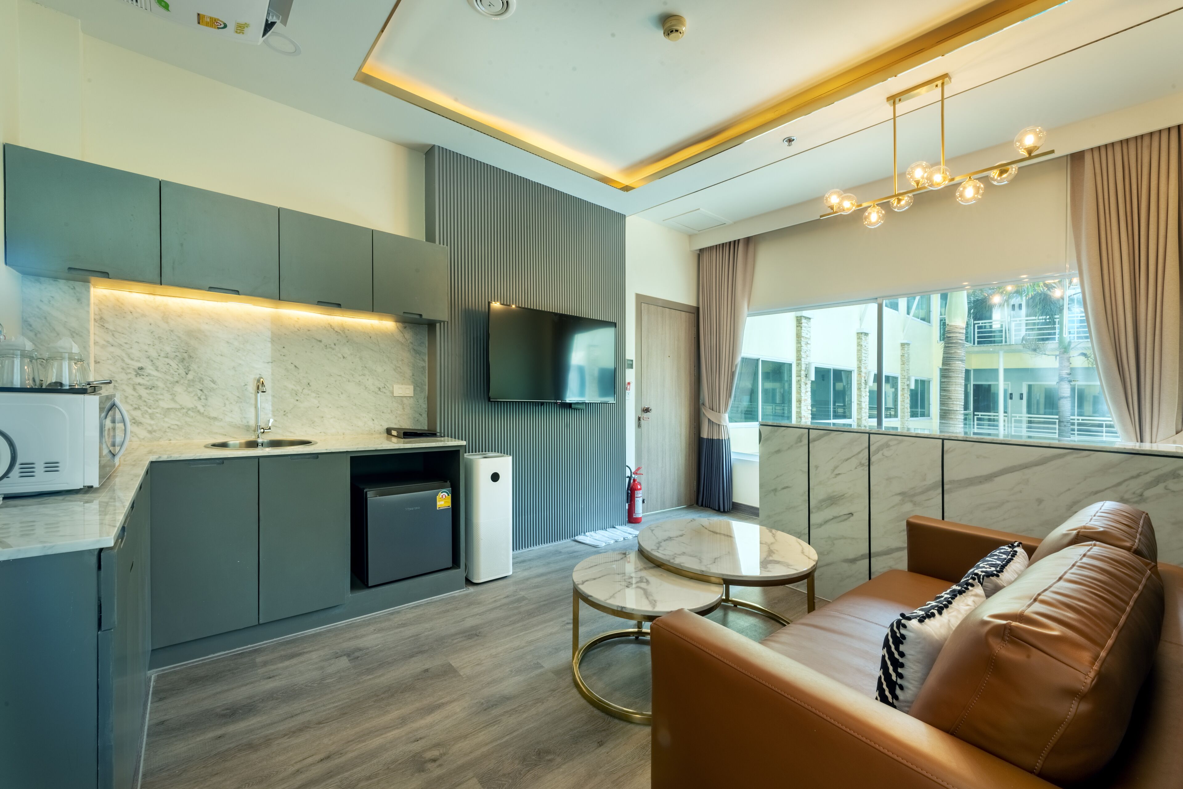A modern kitchen with a built-in TV, a dining area with a marble table, and a leather sofa.