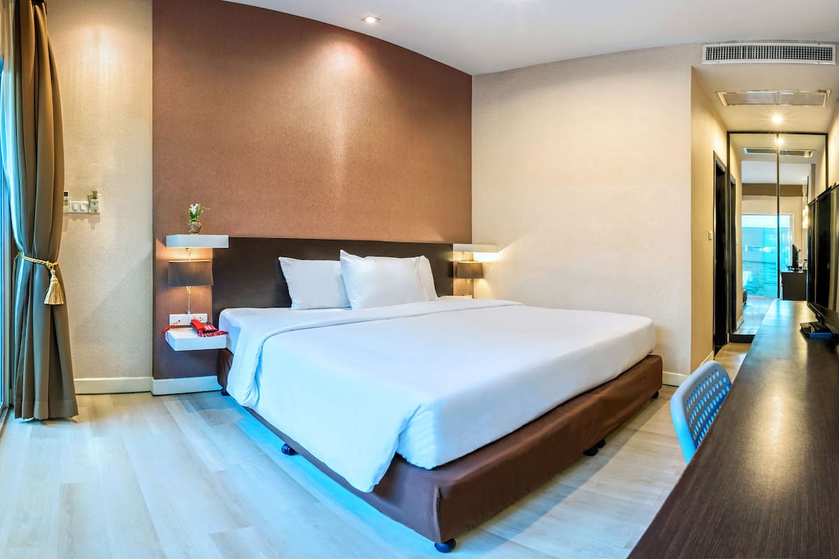 Habitación de hotel moderna con una cama grande, mesitas de noche, televisión y vistas a la piscina.
