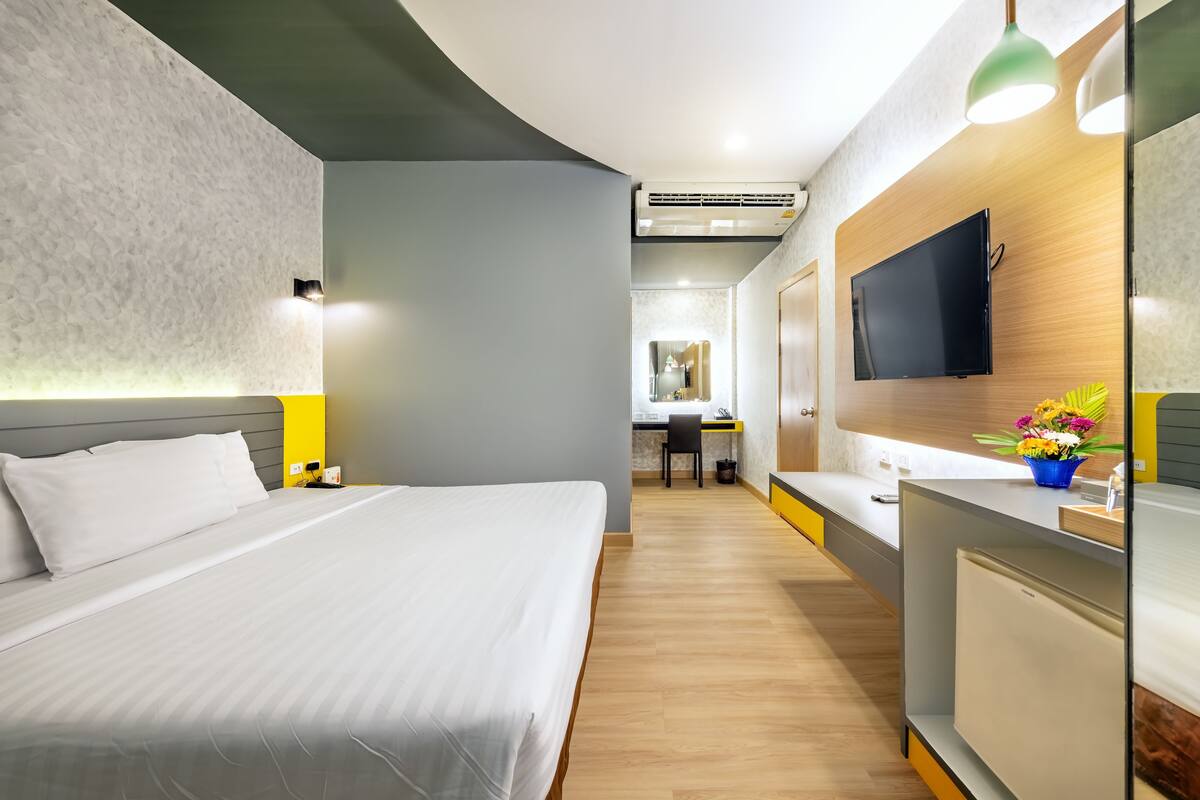 Una habitación de hotel moderna con una cama grande, un escritorio y un televisor fijado a la pared.
