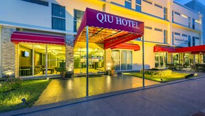 Um hotel com um toldo vermelho bem grande exibindo o nome 'QIU HOTEL'.