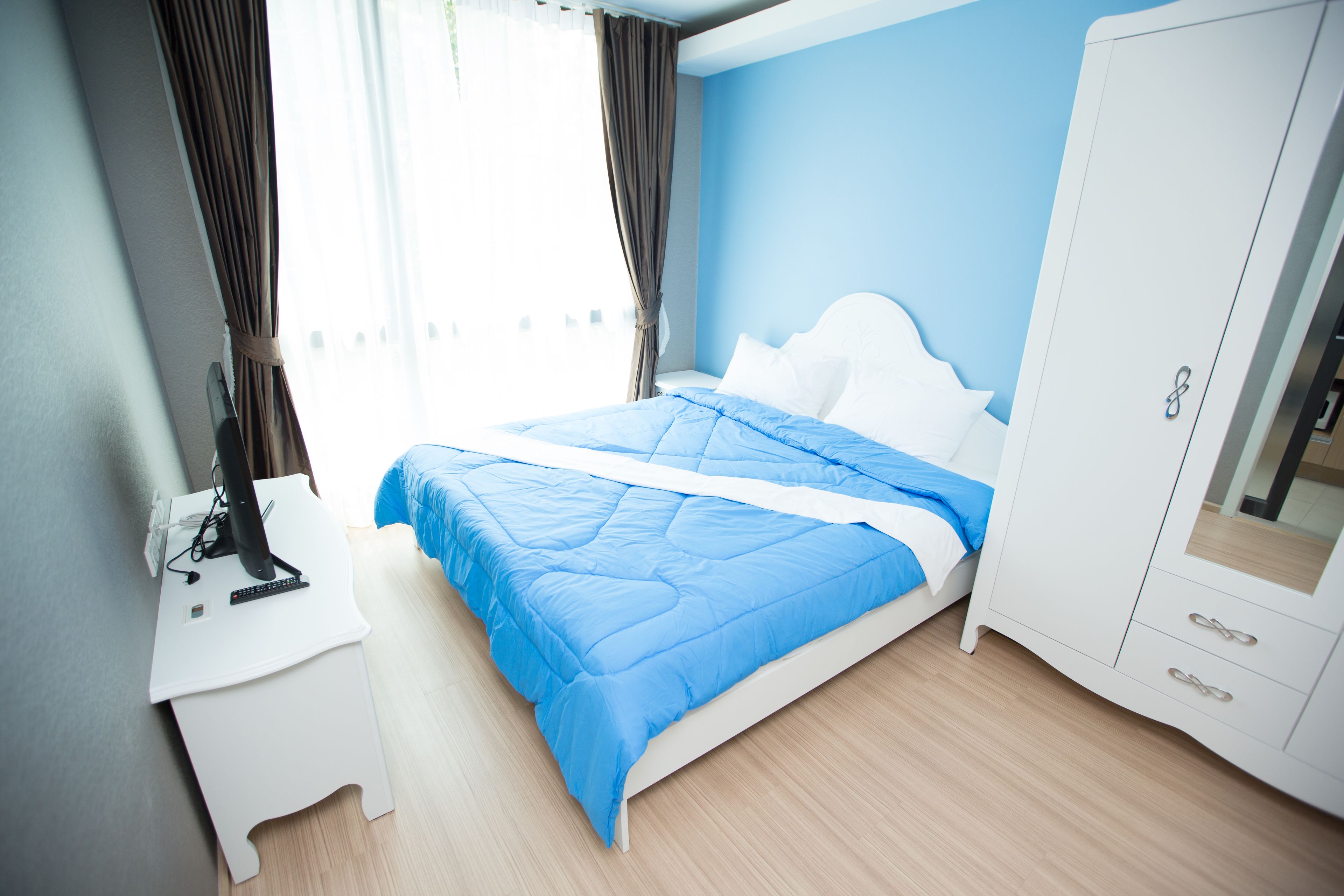 A bedroom with a bed, a desk, and a wardrobe.