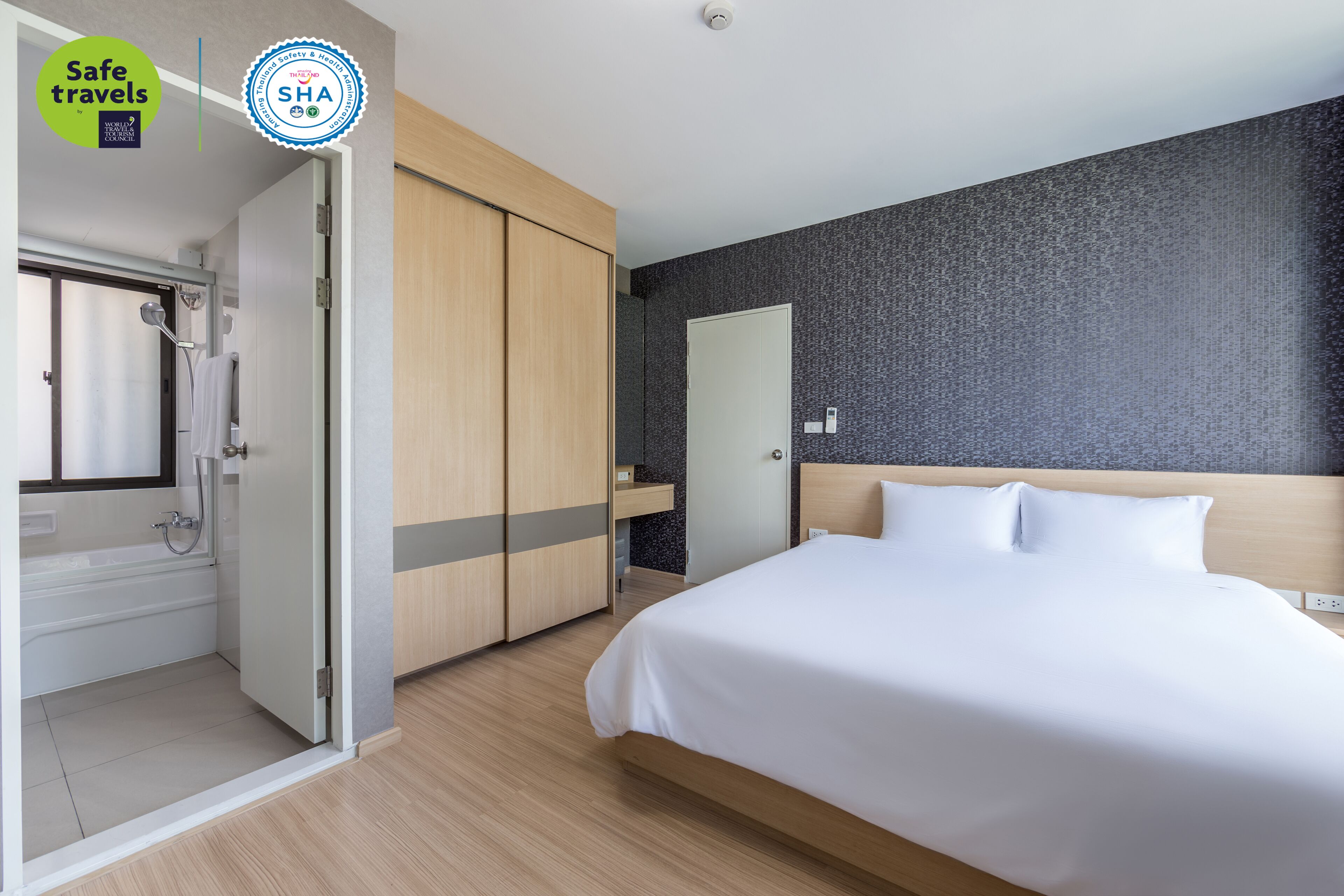 Ein modernes Hotelzimmer mit Bett, Dusche und Schrank.