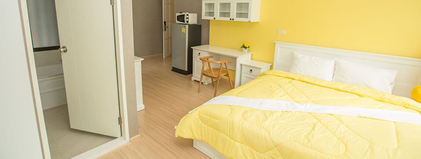 A bedroom with a bed, a desk, and a chair.