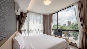 A hotel room with a large bed, a TV, and a view of the cityscape through the window. - Like Sukhumvit 22 (Bangkok)