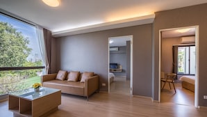 A modern hotel room with a sofa, a coffee table, and a view of the city. - Like Sukhumvit 22 (Bangkok)