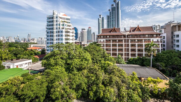 A cityscape with modern high-rise buildings, traditional architecture, and lush greenery. - Like Sukhumvit 22 (Bangkok)