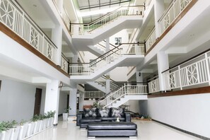 A multi-level atrium with a central staircase, white railings, and a seating area with black sofas. - Urban House 195 (Chiang Mai)